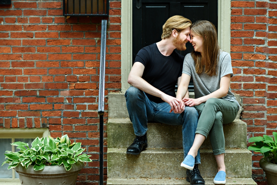 An engaged couple sit on the stoop of their first apartment in Philly.